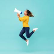 Femme qui saute avec un mégaphone sur un fond bleu